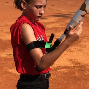 youth female player holding a bat using swingrail swing trainer